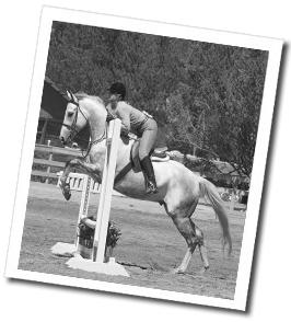 Melinda Hughes with her horse, Charlie, jumping at a horse show.